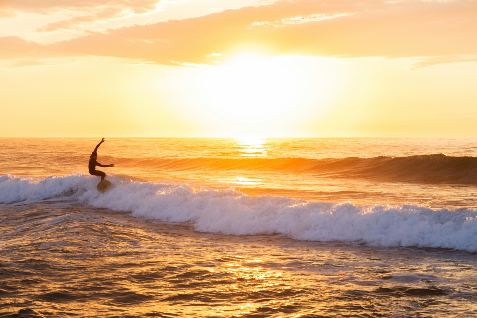夕陽を浴びながらサーフィンの練習をする一人のシルエット